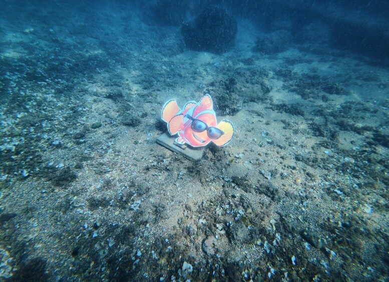 An underwater scene with a colorful fish decoration on the ocean floor. 4