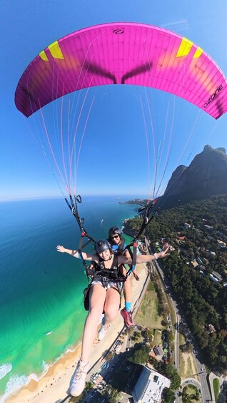 Two people paragliding over a coastal area with a clear view of the ocean and a mountainous landscape. 5