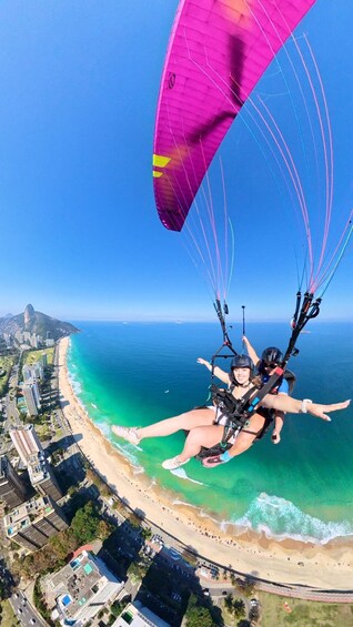 A person paragliding over a coastal area with buildings and a beach. 2