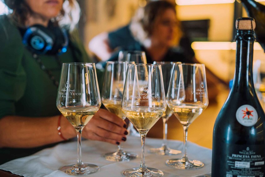 A table with several wine glasses filled with white wine and a bottle of Princess Fanta. 4