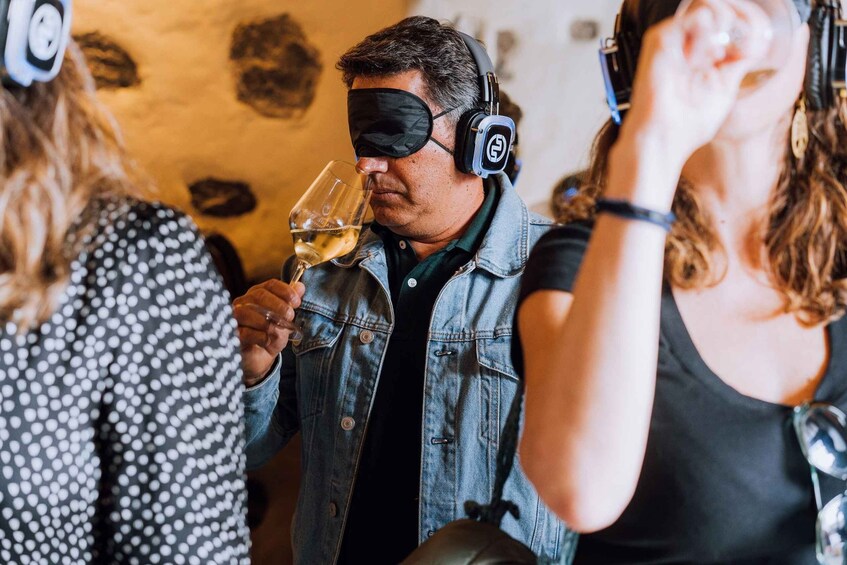 A person wearing headphones and holding a glass of wine. 1