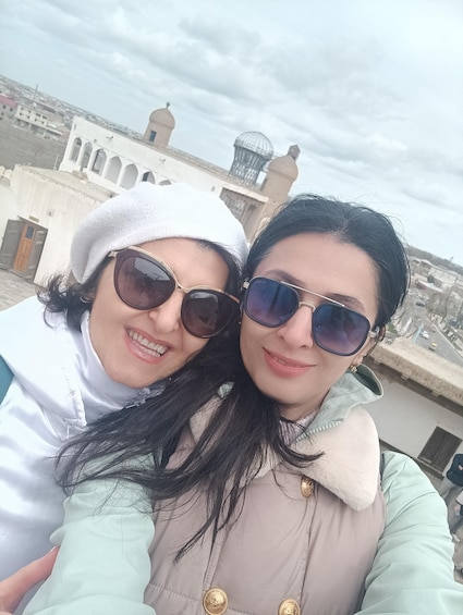 Two people taking a selfie with a historic building in the background. 1
