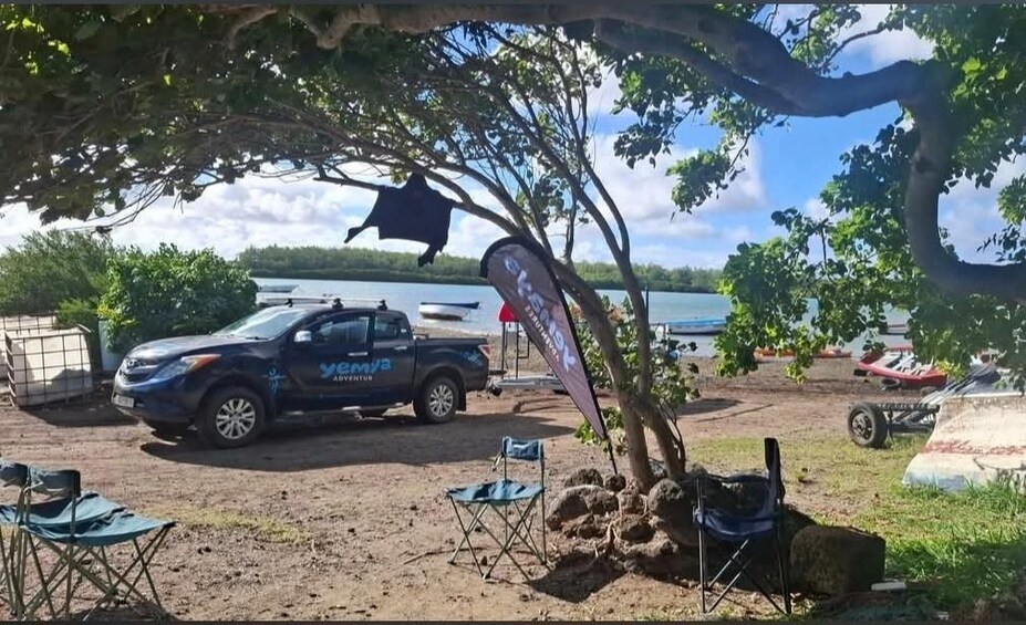 A vehicle parked near a lake, a flag, and a tree. 2