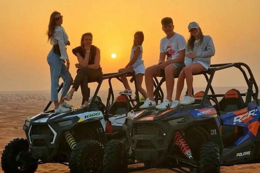 A group of people sitting on off-road vehicles at sunset. 5