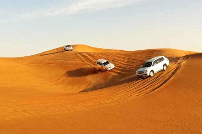 A desert landscape with white vehicles navigating sand dunes. 3