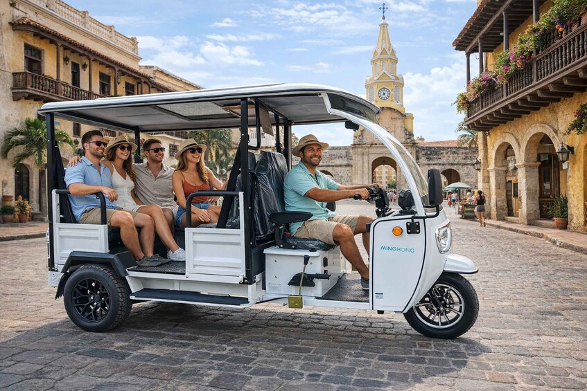 A white golf cart with four passengers on a cobblestone street. 1