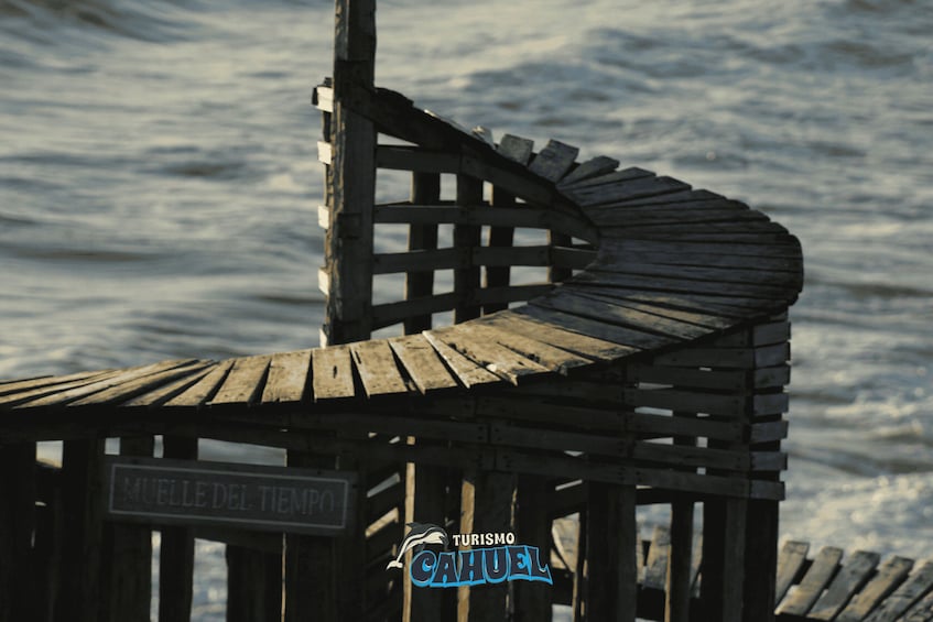 A wooden structure with a sign reading 'Muelle del Tiempo' and a logo for 'Turismo Cajuela.' 3