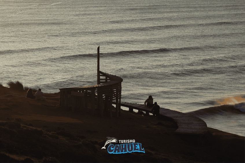 A beach with a wooden structure, waves, and a pier. 5