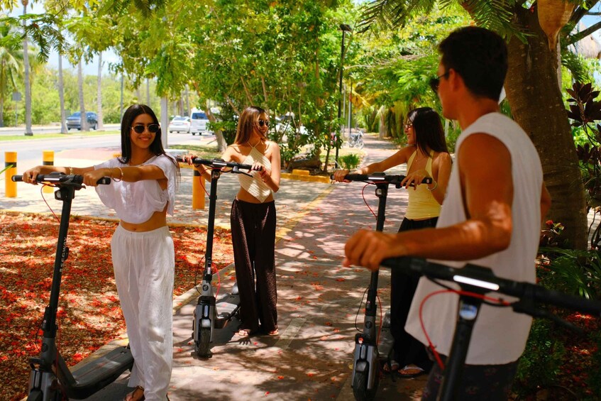 People riding electric scooters on a tree-lined path. 2