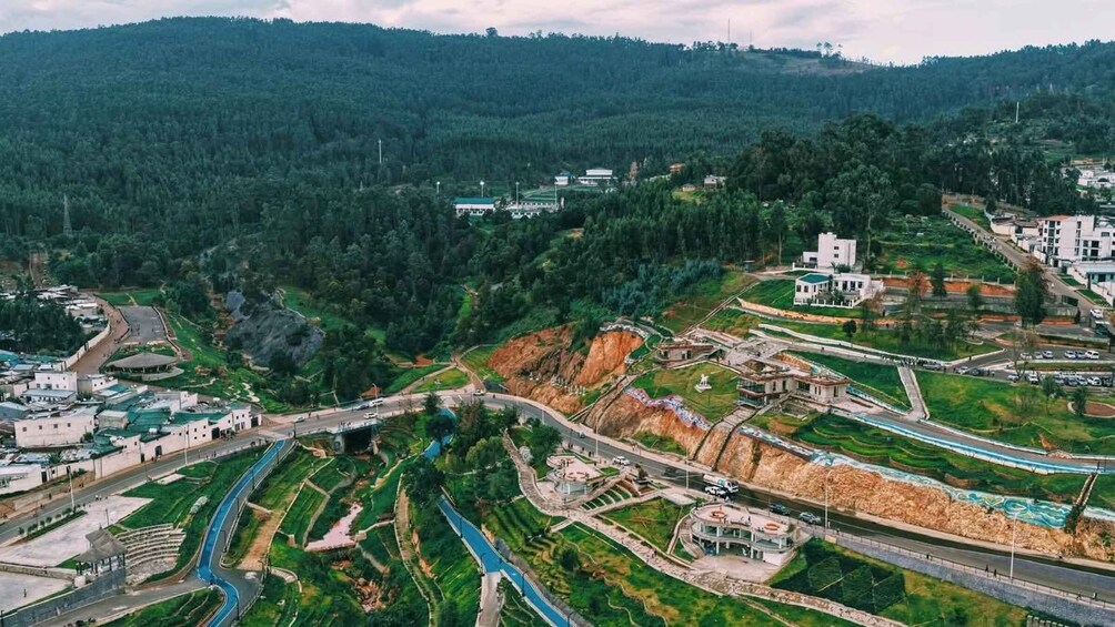 A mountainous landscape with a winding road, green fields, and scattered buildings. 4