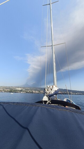 A sailboat with a clear sky and a distant cityscape. 2