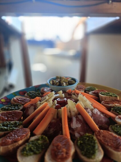 A plate of assorted appetizers including bruschetta, cheese, and vegetables. 4