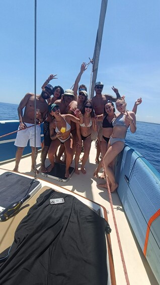 A group of people on a boat with a clear blue sky and calm sea in the background. 5