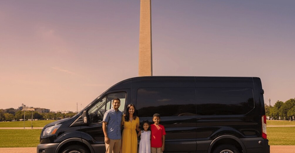 A family of four standing in front of a black van with the Washington Monument in the background. 3