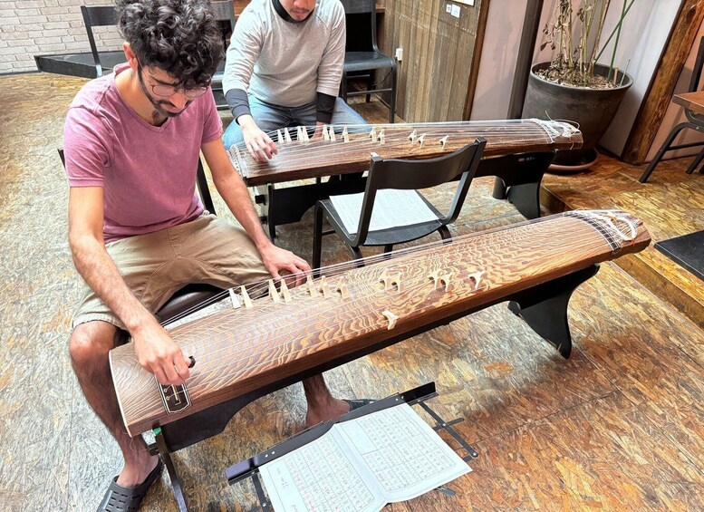 A person playing a stringed musical instrument with a sheet of music on a stand. 2