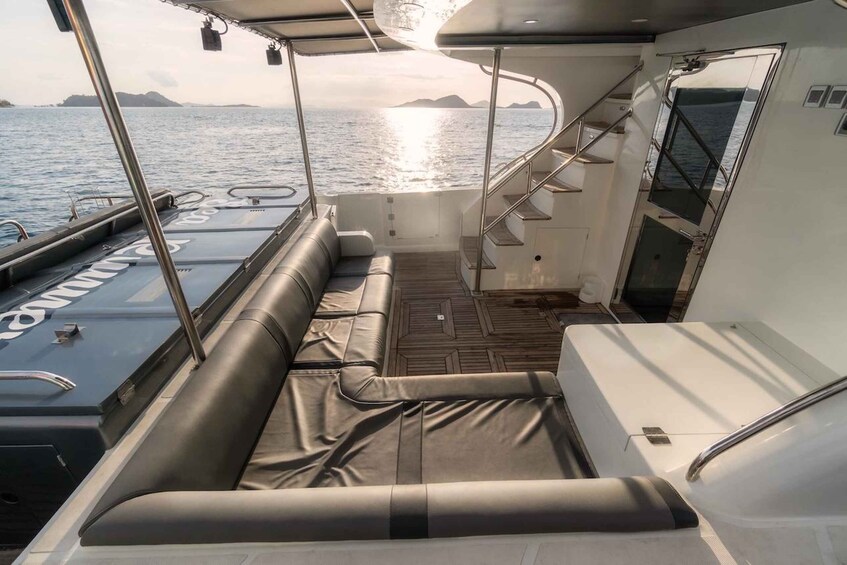 A boat deck with a seating area, a staircase, and a view of the sea. 2