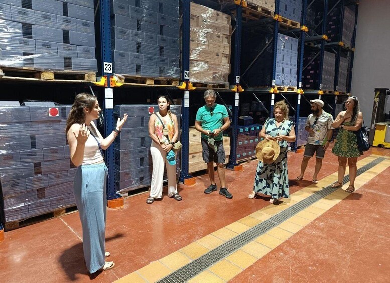 A group of people standing in a warehouse aisle with shelves stocked with boxes. 4