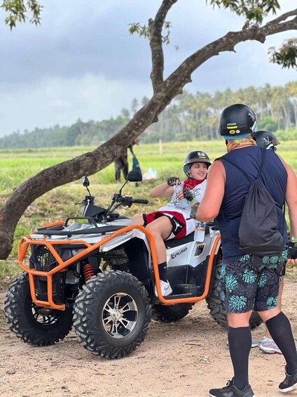 A person on an ATV with a large tree in the background. 2