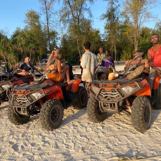 A group of people on ATVs in a sandy area with trees in the background. 5