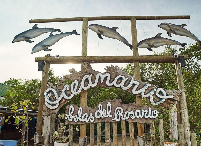 A wooden sign with dolphins and the text 'Oceanario Las del Rosario'. 2