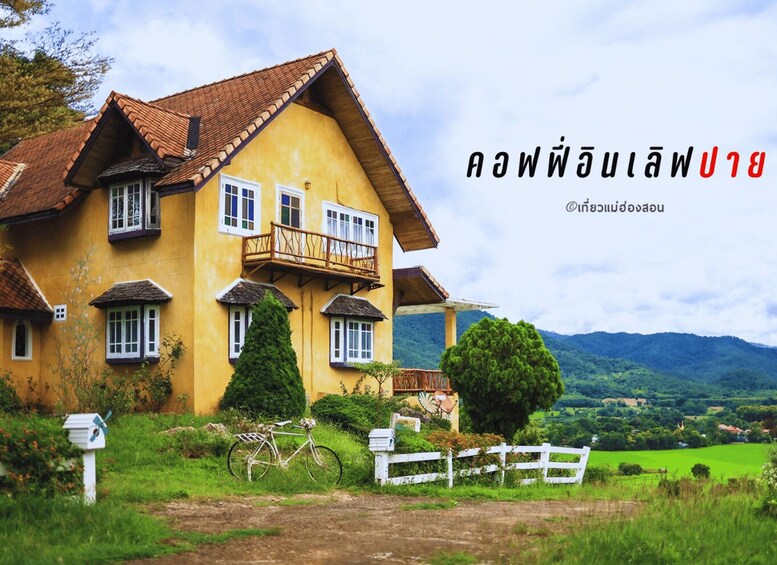 A yellow house with a red roof, surrounded by greenery and hills. 5