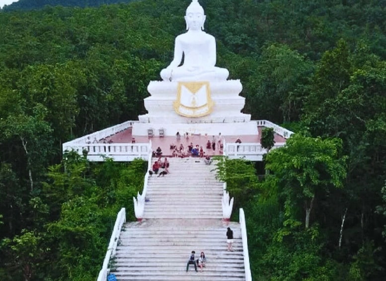 A large white stupa with a golden emblem, surrounded by lush greenery and a staircase leading up to it. 3
