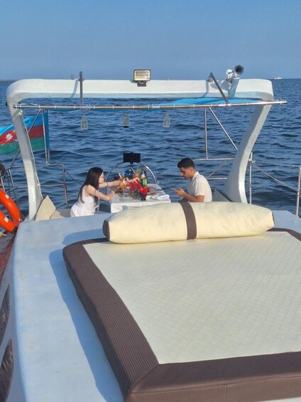 A boat with two people dining at a table, surrounded by water. 3