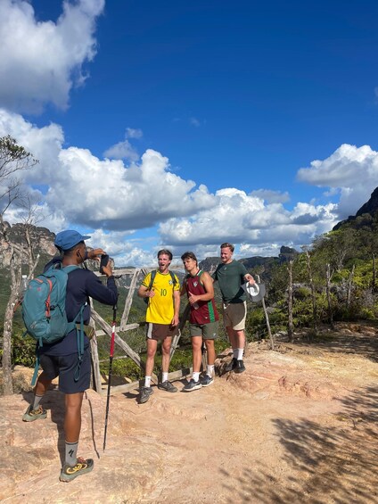 Four people standing on a dirt path with a mountainous landscape in the background. 5