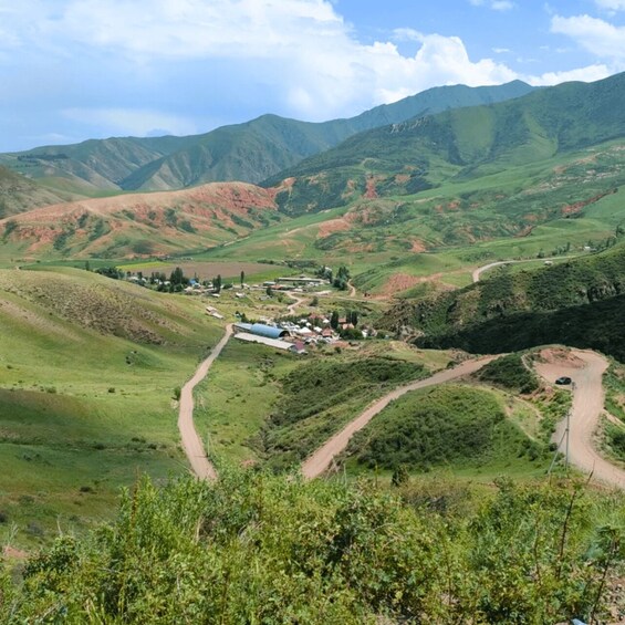 A valley with winding roads, green hills, and a small settlement with buildings. 5