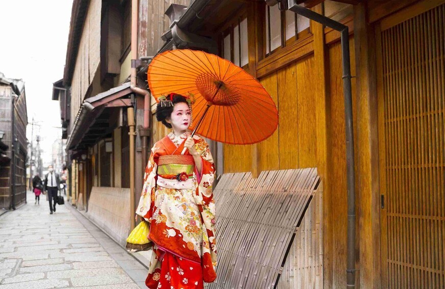 Perinteisiin japanilaisiin vaatteisiin pukeutunut henkilö kävelee katua pitkin. 1