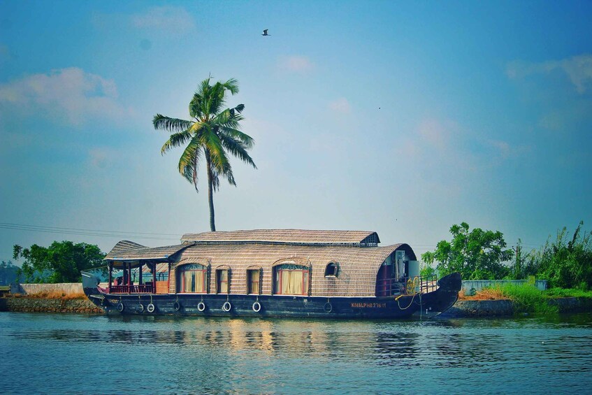 A houseboat with a thatched roof, palm trees, and calm water. 1
