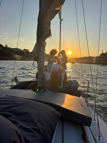 A sunset on a calm river with a sailboat and people on board. 4