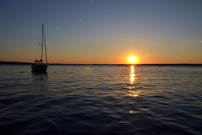 A sailboat on calm water during sunset. 2