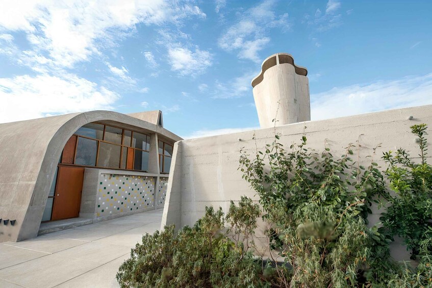 A modern building with a curved facade, a tall cylindrical tower, and a patterned wall. 4