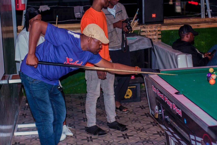 A person playing pool at a table with a green felt surface. 1