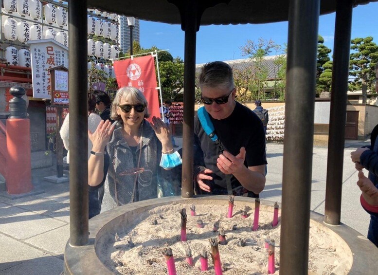A shrine with a circular stone structure, incense sticks, and Japanese characters on banners. 3