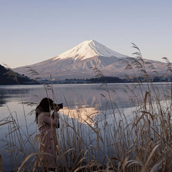 A person taking a photograph of a snow-capped mountain by a calm lake. 5