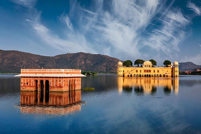 A calm lake with a reflection of a building and a hill in the background. 2