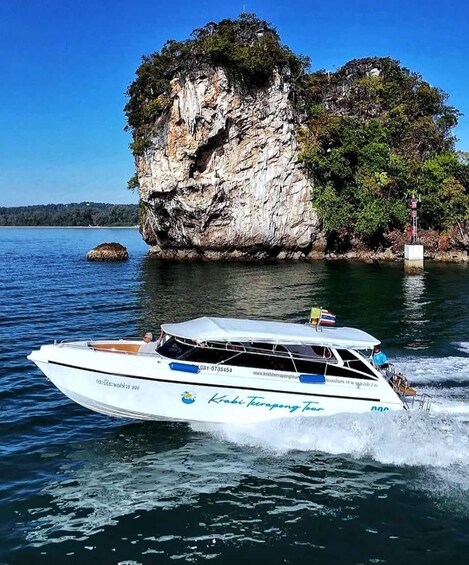 A boat named 'Krabe Terapong Tuan' on a lake with a rocky island in the background. 1