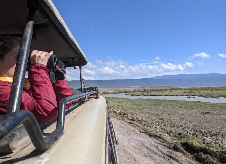 Una persona in un veicolo safari con vista su un fiume e montagne lontane. 5