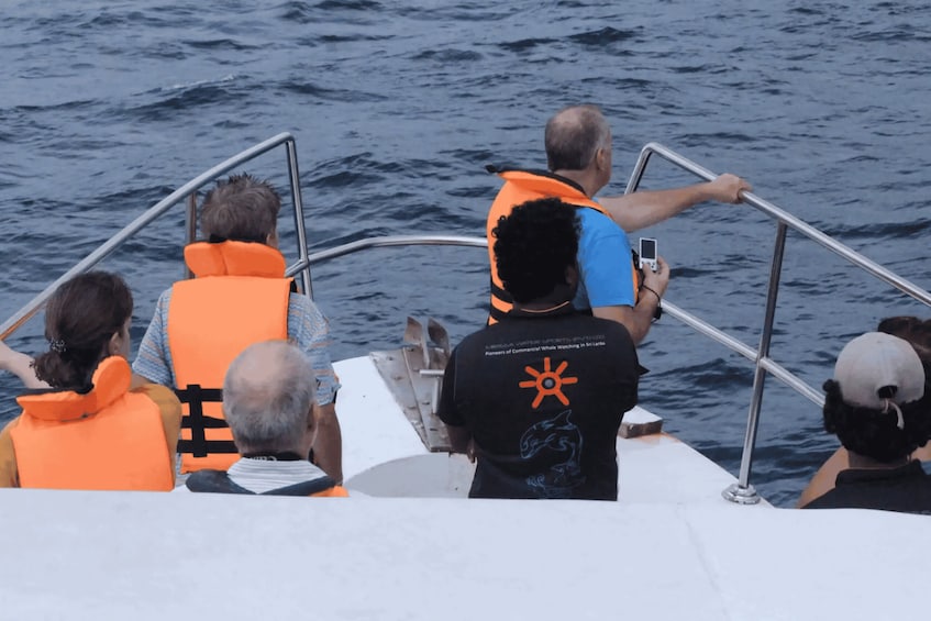 People on a boat wearing life jackets, with one person taking a photo. 5