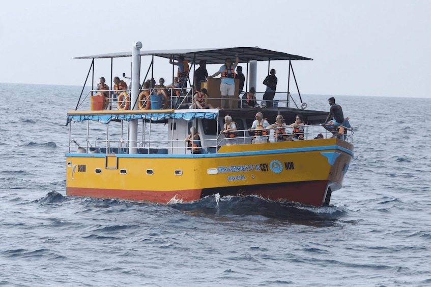 A yellow and blue boat with people wearing life jackets on the water. 4
