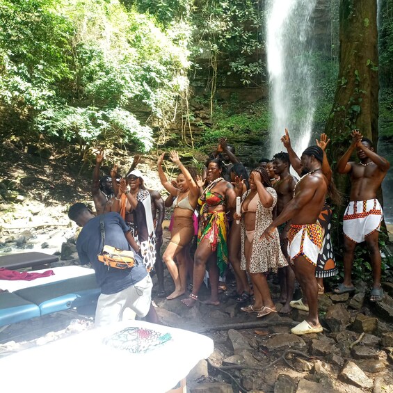 A group of people enjoying a waterfall in a forested area. 4