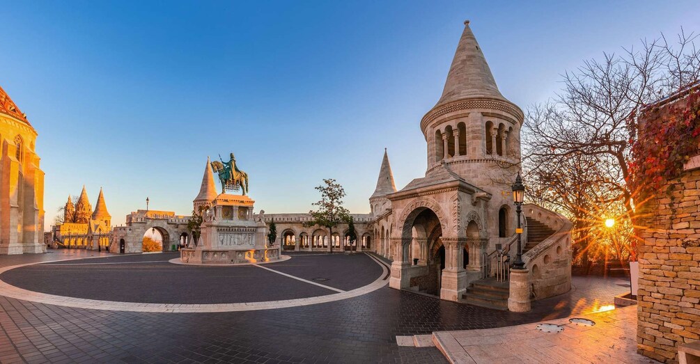 A historic square with a central monument, a tall tower, and a bridge in the background. 3