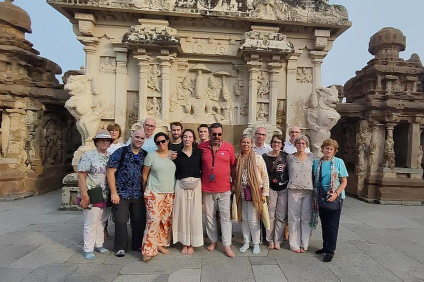 A group of people standing in front of an intricately carved stone structure with detailed sculptures and architectural elements. 1