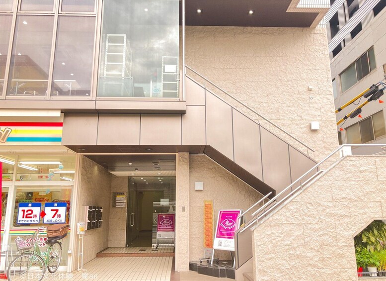A multi-level building with a staircase, a bicycle, and a storefront with a sign indicating operating hours. 2