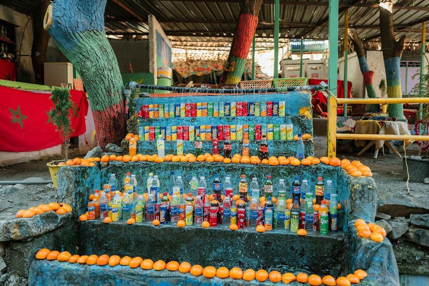 A tree with colorful paint and bottles of beverages arranged on its branches. 3