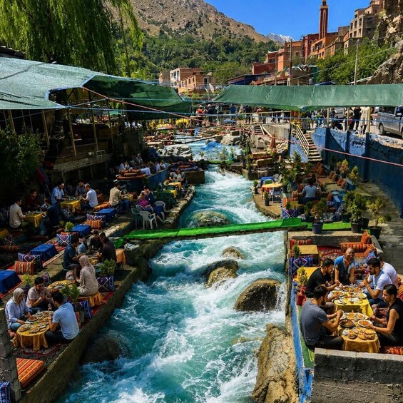 A bustling riverside market with people dining and socializing. 5