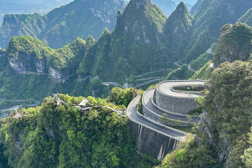 A winding mountain road surrounded by lush greenery and steep cliffs. 2