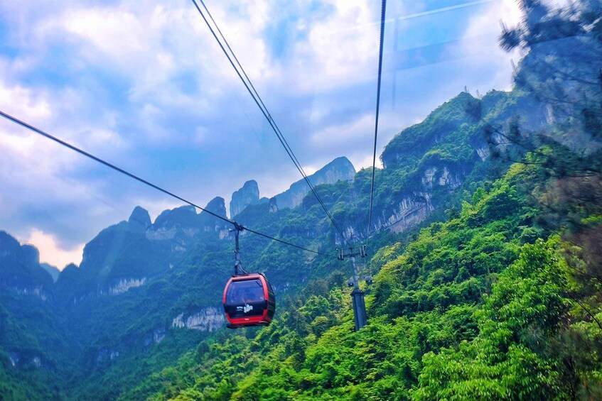 A cable car suspended over a lush green valley with mountains in the background. 5